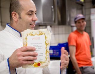 Een man deelt de certificaten uit in Gelateria David