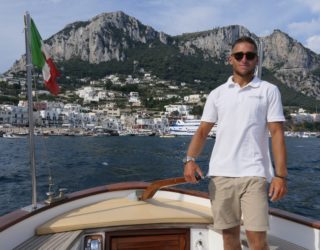 Kapitein van de gozzo boot met Capri op achtergrond