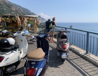 Drie Vespa's die aan de rand van de Amalfitaanse kust staan