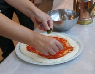Pizza beleggen met basilicum in Napels