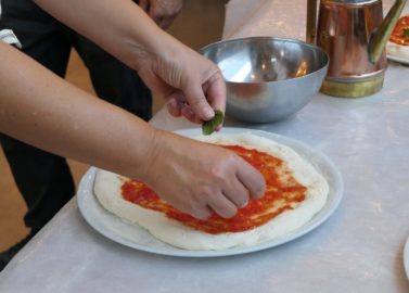 Pizza beleggen met basilicum in Napels