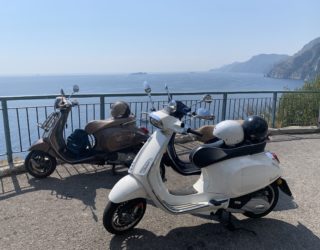 Twee Vespa's die voor een prachtig zicht van de Amalfitaanse kust staan