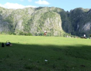 Paard en ruiter naast de Mural de la historia in vinales