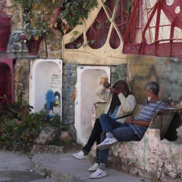 Bewoners van Callejon de Hamel op bankje gemaakt uit badkuip tijdens elektrische fietstocht door Havana