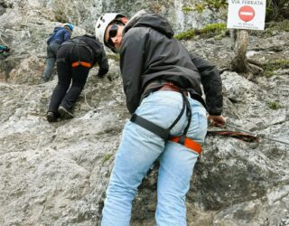 Familie klimt op de rotsen van de Via Ferrata in Banff