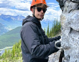 Tiener klimt op de rotsen bij de Via Ferrata in Banff