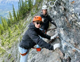 Kinderen klimmen op de rotsen bij de Via Ferrata in Banff