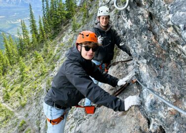 Kinderen klimmen op de rotsen bij de Via Ferrata in Banff
