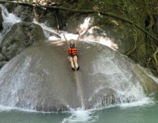 Zalig glijden van de rotsen in de Erawan Falls