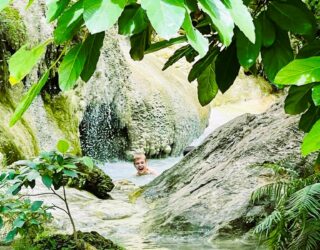 Kind zwemt in de Erawan watervallen in Thailand