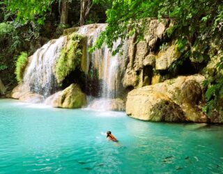 Kind zwemt tussen de vissen in de Erawan watervallen