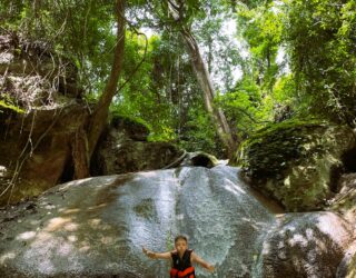 Kind glijdt van de rotsen in de Erawan watervallen