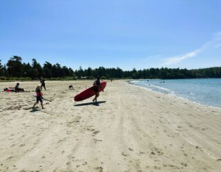 Kind surft op het strand bij hotel Tofino