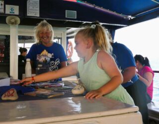 Vrijwilligers geven kinderen uitleg op de boot over schildpadden in Zakynthos