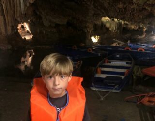 Kind vaart met boot in ondergrondse grotten van Diros