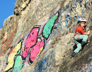 Kind klimt op rots in Slovenië