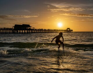 Kind bij zonsondergang strand Naples