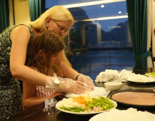 Mama en kind maken zelf springrolls tijdens cruise in Halong Bay