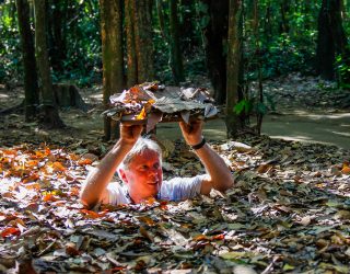 Man komt uit smalle opening van Cu Chi Tunnel