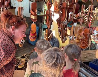 Kinderen verkennen kraampje dat sandalen verkoopt op de markt