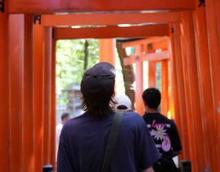 Jongen wandelt door rode torii-poorten Japan