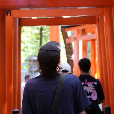Jongen wandelt door rode torii-poorten Japan