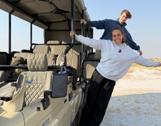 Twee tieners hangen aan jeep in Onguma