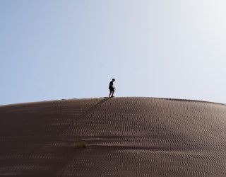 Tiener op zandduinen in Oman