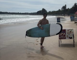 Tiener met surfplank op het strand van Weligama