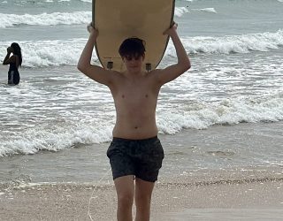 Tiener stapt met surfplank op strand in Weligama