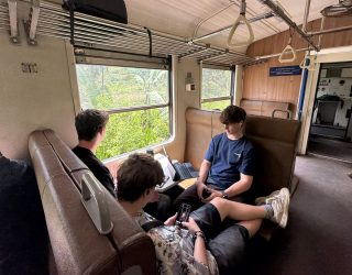 Tieners op trein door theeplantages in Sri Lanka